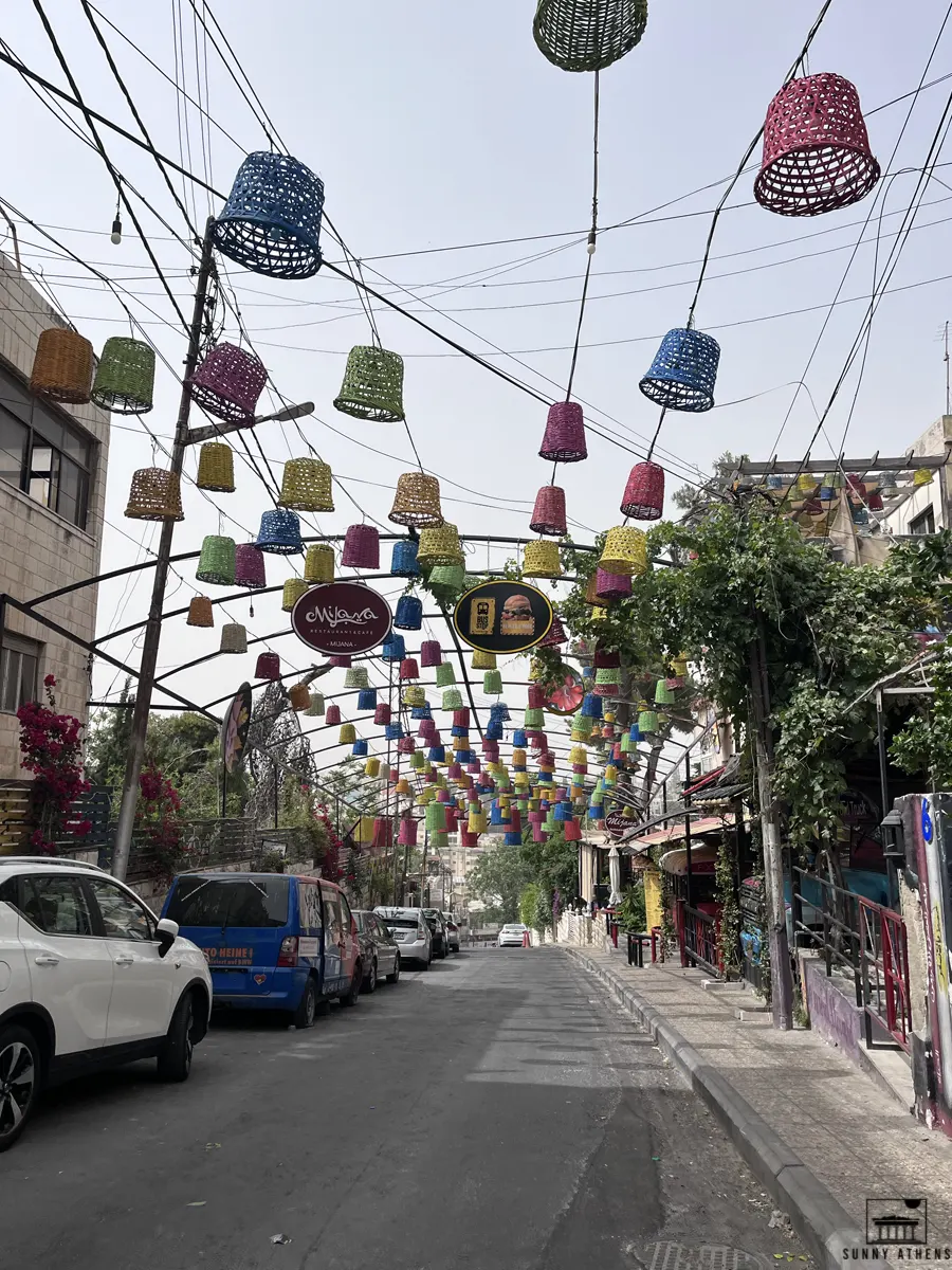 Colorful baskets hanging above Rainbow Street in Amman, adding to its distinctive charm.