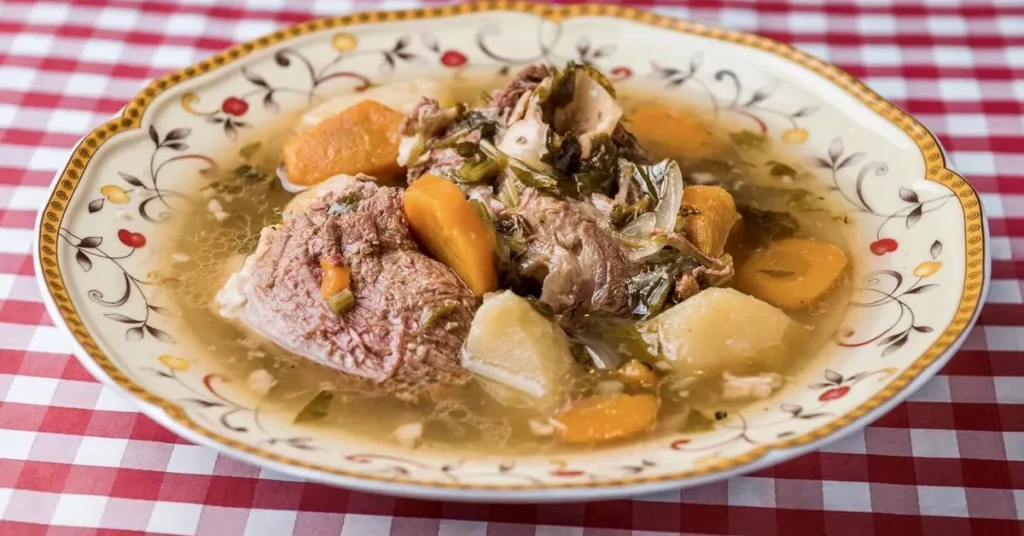 A bowl of traditional Greek meat and vegetable stew on a red and white checkered tablecloth.