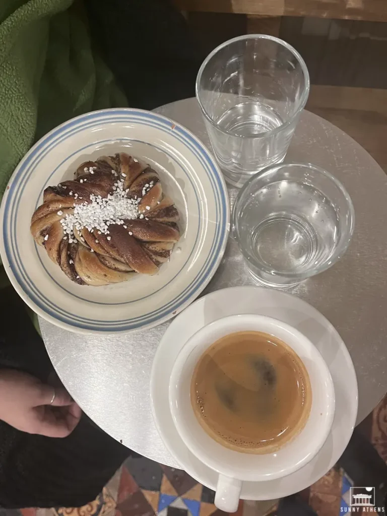 A close-up of a pastry on a plate with a cup of coffee on a table at Pascal Kaffebar.