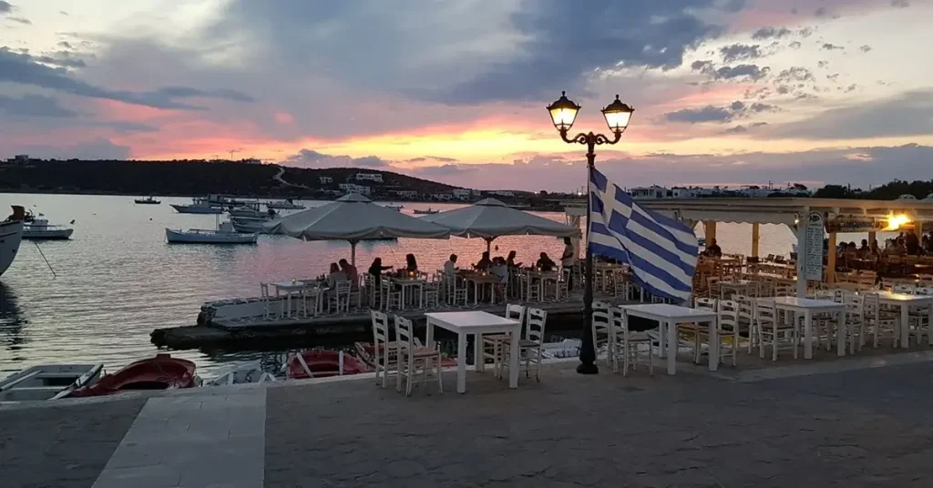 The white tables of Mouragio Tavern, next to the sea, during a summer sunset.