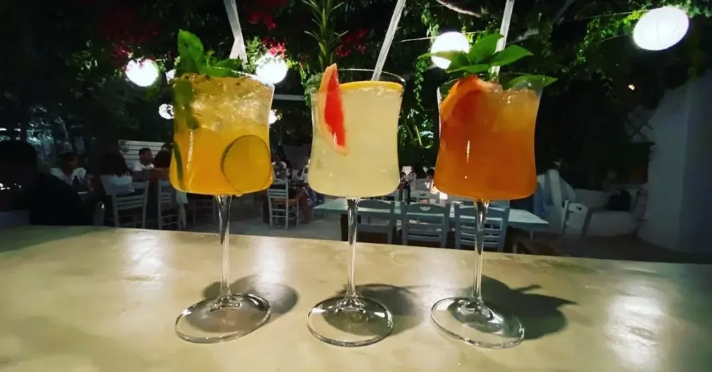 Three colorful cocktails lined up on the bar at The Green Project in Paros, Greece, awaiting service.