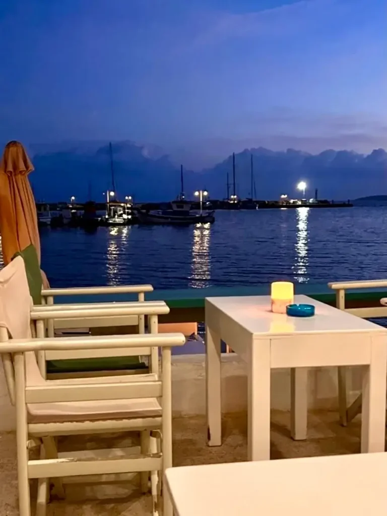 Paros Greece nightlife: Quaint white tables and chairs set by the seaside at Remezzo Bar.