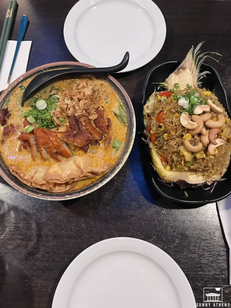 A table at Soul Vegan with a bowl of chicken curry soup and a pineapple filled with fried rice.