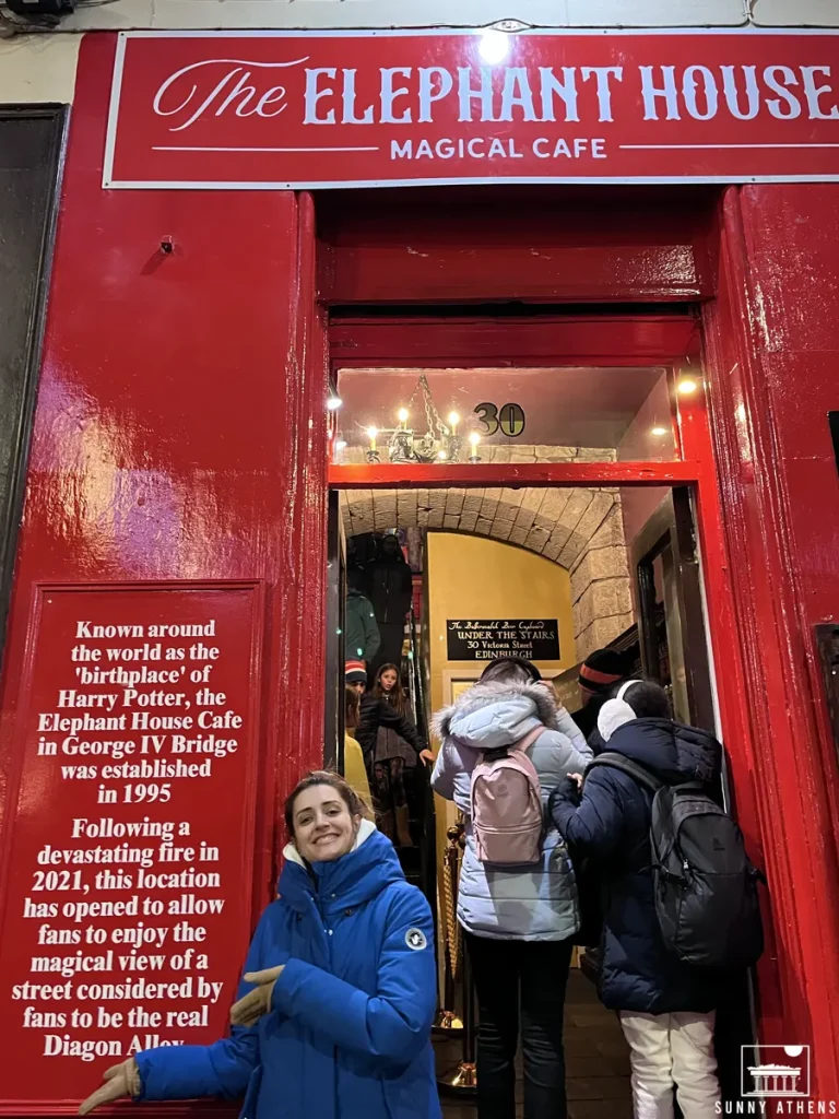 Chrysavgi smiling in front of the red storefront of The Elephant House, known as the 'birthplace' of Harry Potter.