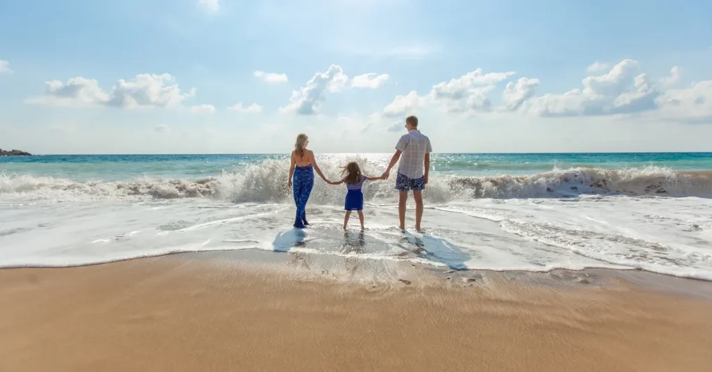 Athens Off-The-Beaten-Path Itinerary For Families: A family holding hands on the beach on a summer day under a clear sky.