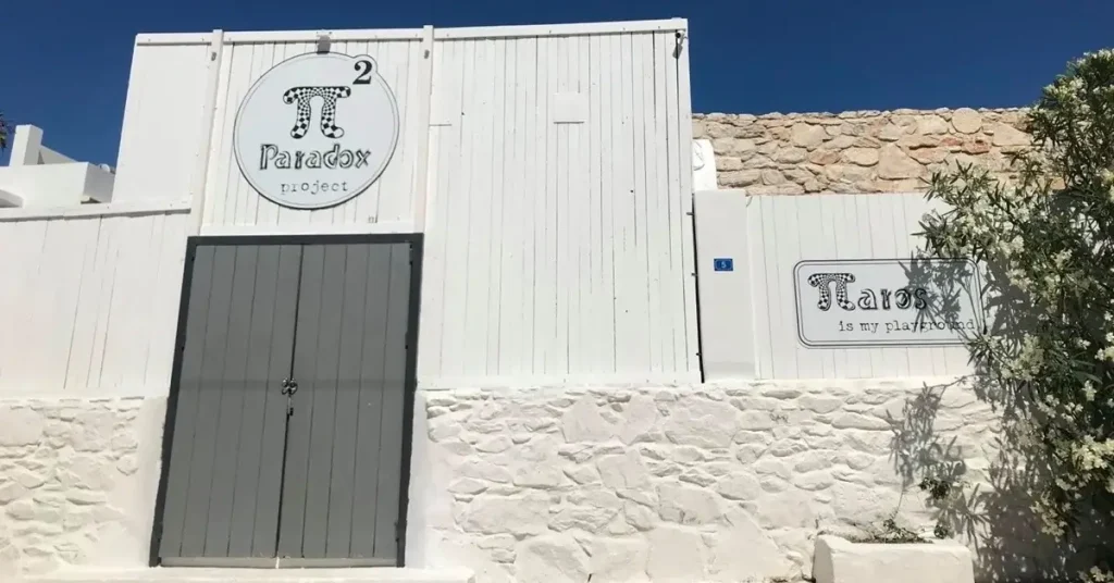 The white wooden entrance of Paradox Project escape room in Paros, Greece.