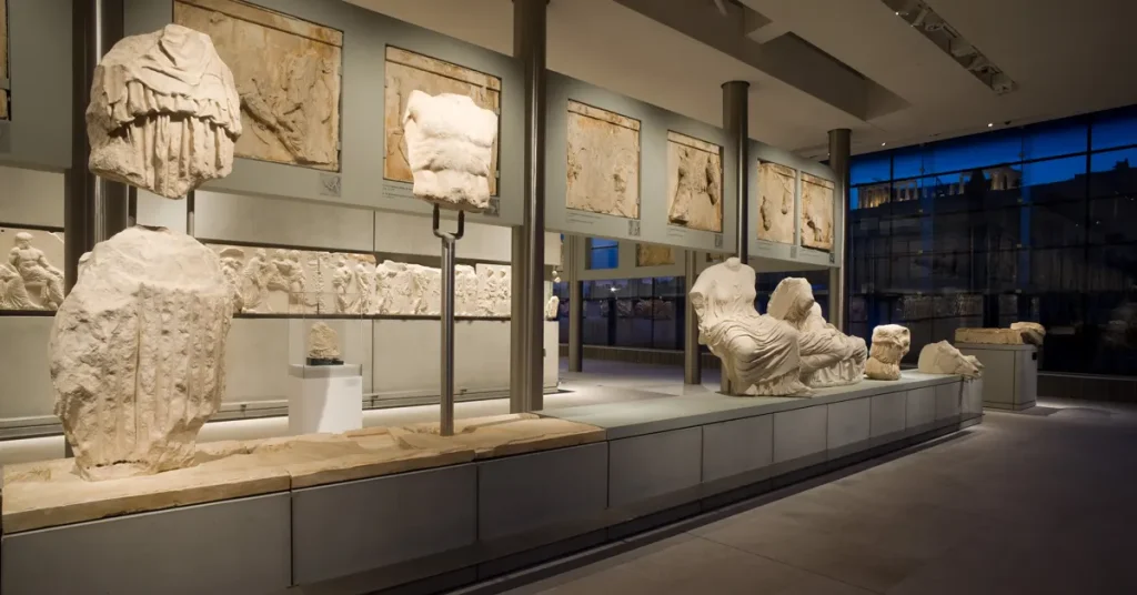 The east pediment of the Parthenon at the Acropolis Museum with the illuminated Acropolis in the background.