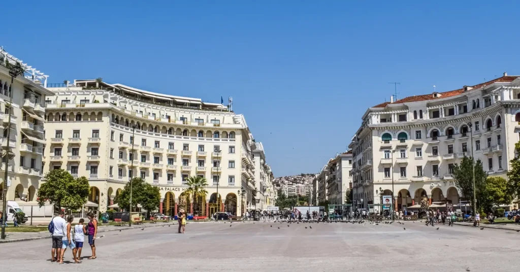 Aristotelous Square in Thessaloniki, with people walking by and surrounded by grand, white buildings.