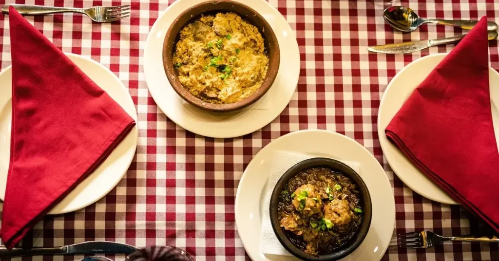 Fërgesë and tavë kosi, typical dishes of Albanian cuisine, served in clay dishes.