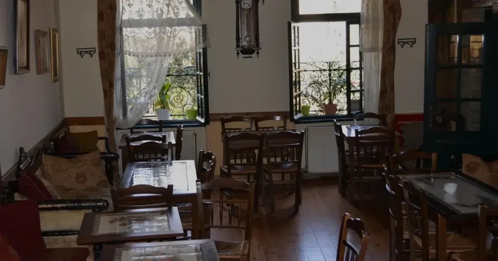 The interior of the traditional Kafeneio restaurant, featuring old wooden chairs and tables, in Plaka, Athens