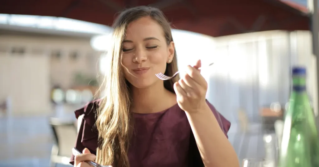 A woman enjoying a slice of pizza at a restaurant.