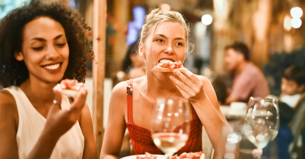 Friends sharing pizzas and drinks at an outdoor restaurant, a scene typically enjoyed on food tours in Athens for foodies.