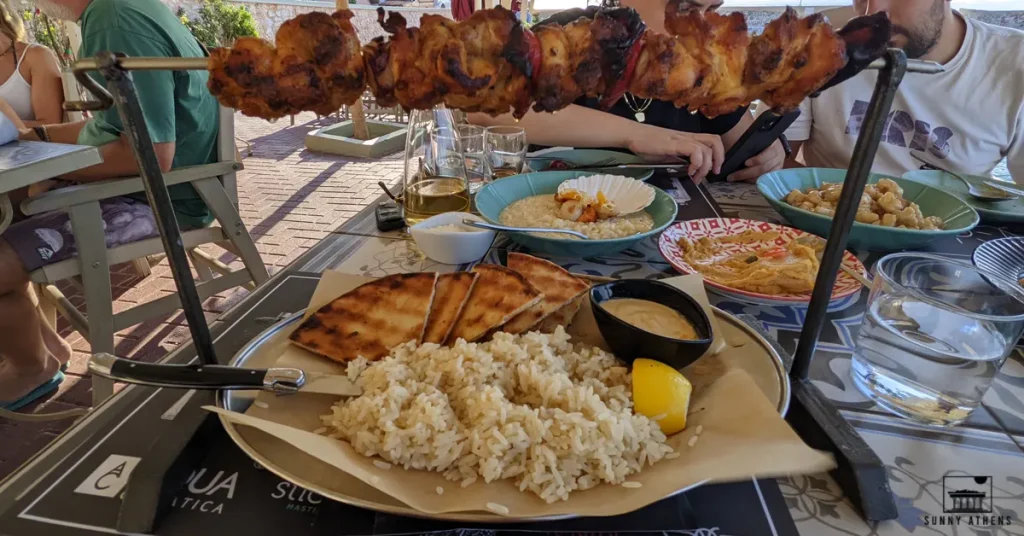 Best Season for Athens: a table full of delicious Greek food, including grilled meat on skewers, rice, and bread, during the Tsiknopempti celebration in Athens.