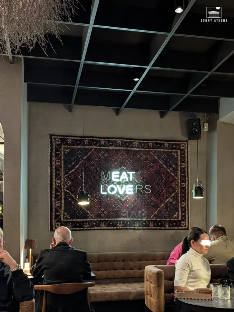 The cozy interior of Meat Lovers Vilnius, with a glowing neon sign on a patterned wall.