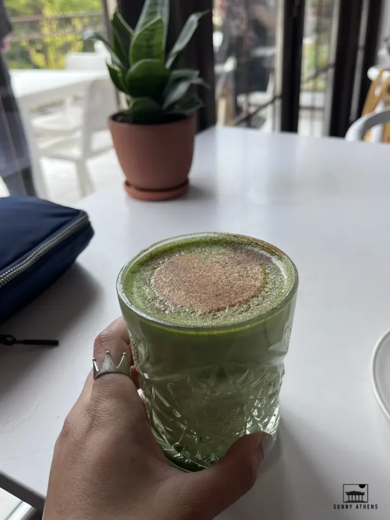 A female hand holding glass of matcha latte, served at Strange Love Coffee Roasters in Vilnius.