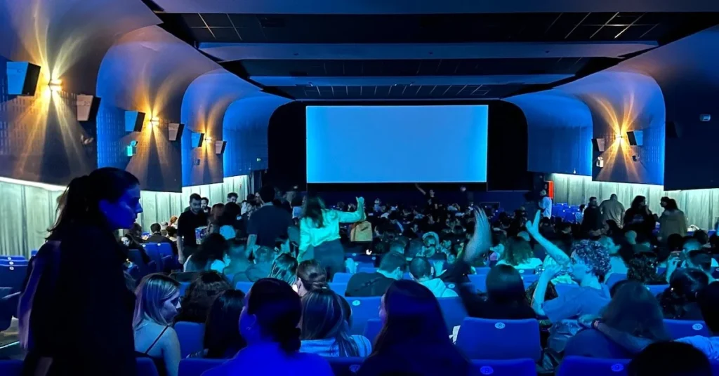 A lively youthful crowd is taking their seats before the start of a movie in the distinctive blue screening room of Opera cinema one of the best indoor cinemas in Athens center