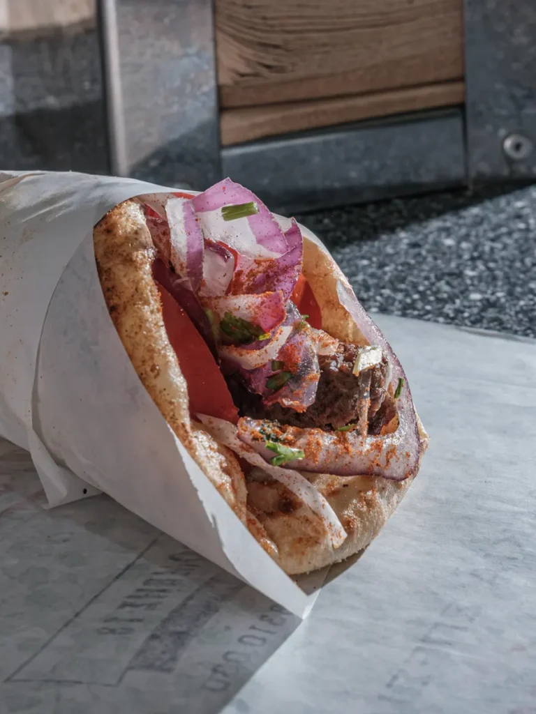 Best traditional souvlaki in Athens: A freshly made souvlaki filled with meat, onions, tomatoes, and red pepper.