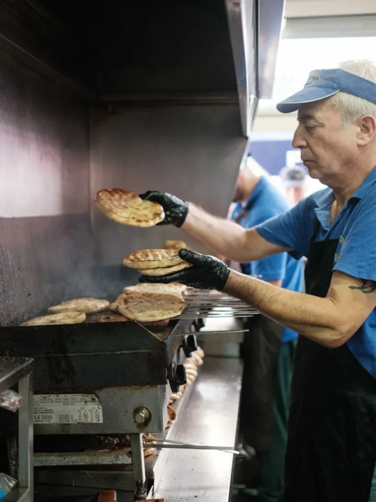 Best traditional souvlaki in Athens: A cook grills pita bread on a large grill in the kitchen of Lefteris o Politis.