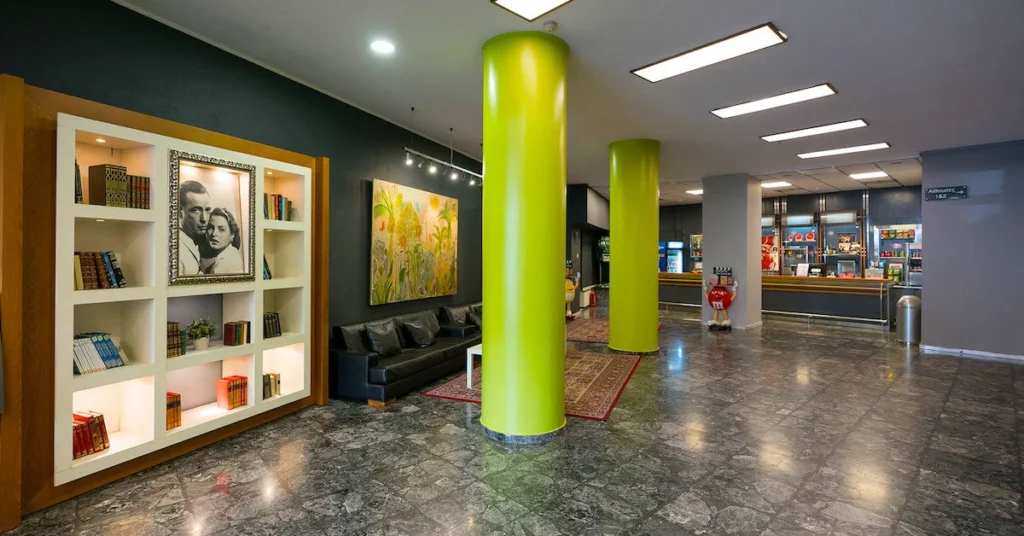 The foyer of Nirvana cinema, one of the best indoor cinemas in Athens center, with two large lime green columns contrasting the grey tiled floor