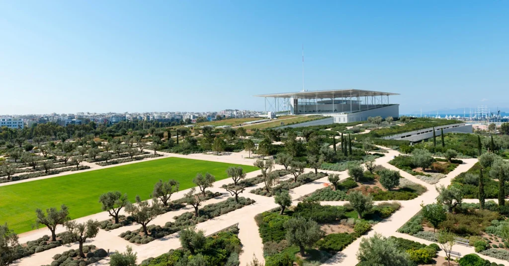 A panoramic view of the SNFCC Stavros Niarchos Park, surrounded by olive trees and set against a clear blue sky.