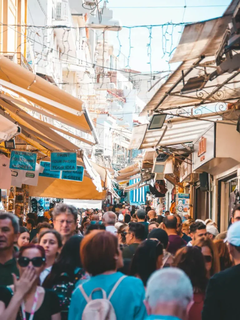 How to escape the crowds in Athens: Crowded marketplace in Monastiraki with narrow streets and colorful awnings.