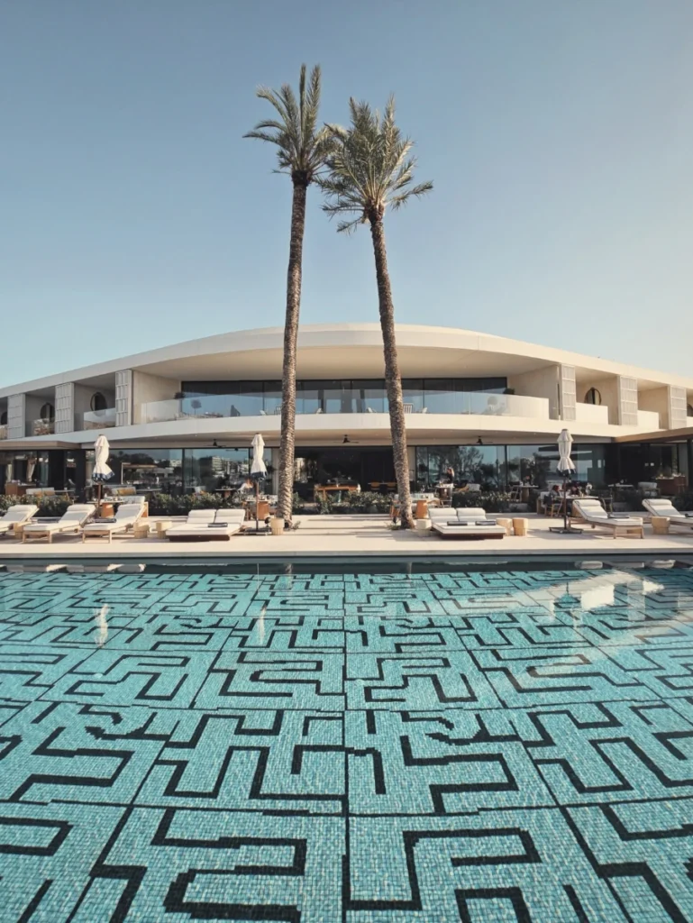 Honeymoon in Athens: The luxurious poolside view of One&Only Aesthesis, Athens, with palm trees and a stylish resort in the background.