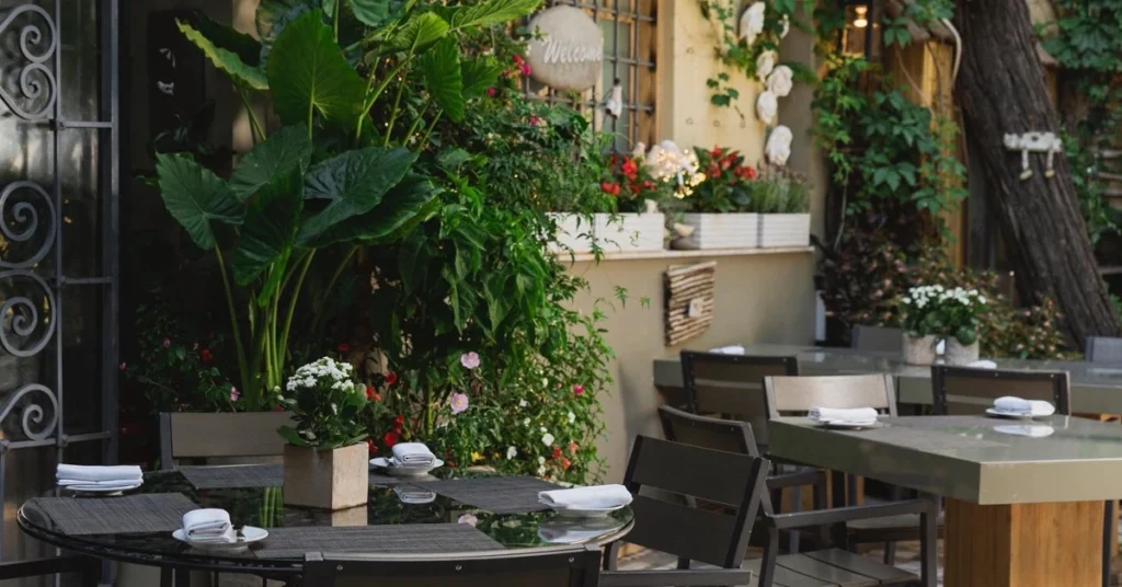 The outdoor dining area of Aleria Restaurant with lush greenery and elegant table settings.