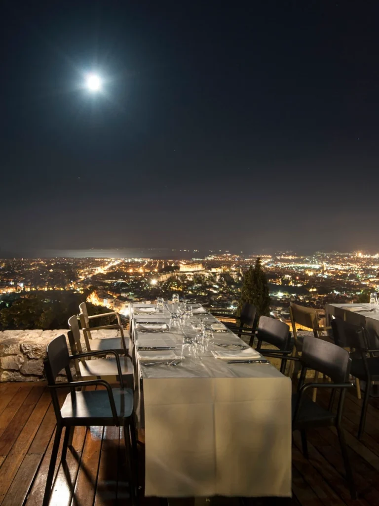 Honeymoon in Athens: a fine dining setup on the Orizontes Lycabettus terrace overlooking Athens at night with a full moon.