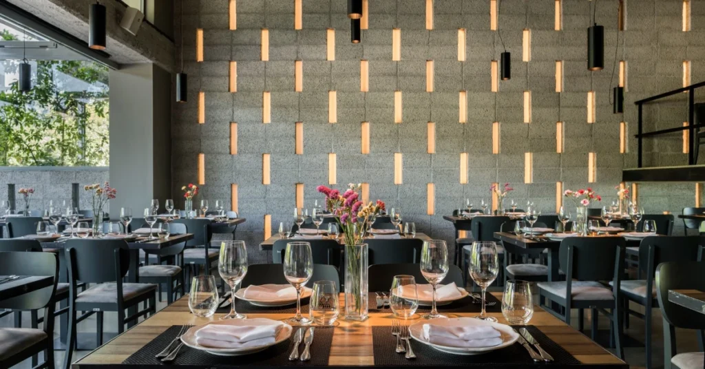 The modern fine-dining restaurant of Vassilenas, with a geometric light-accented wall and elegantly set tables.