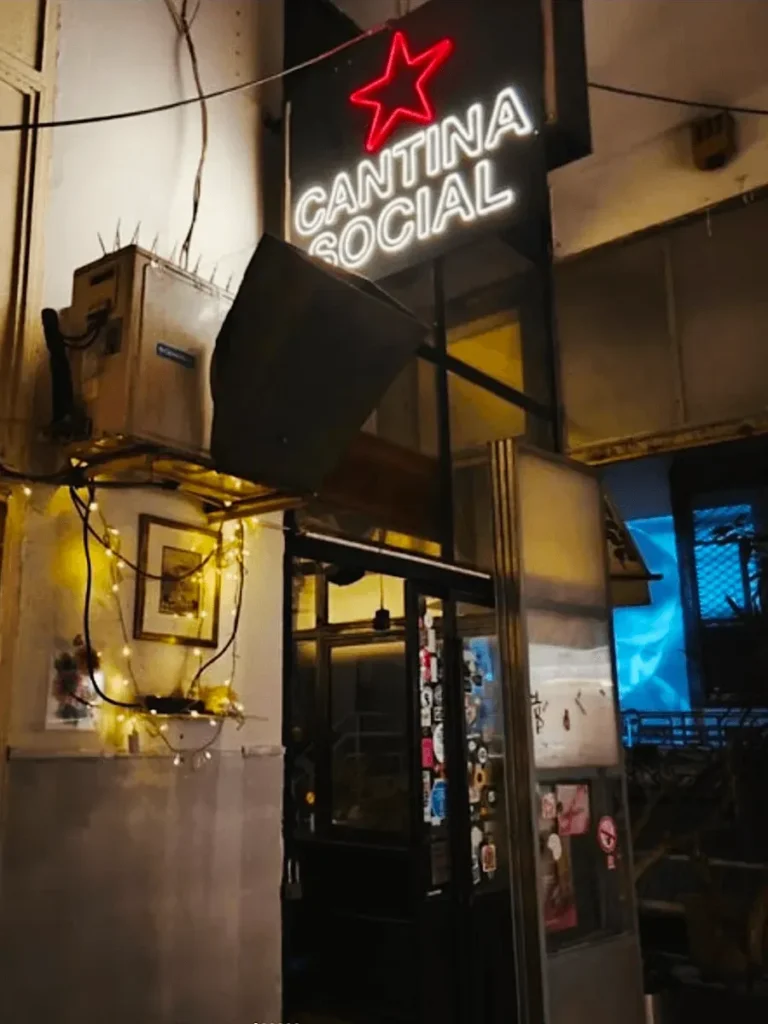 View of the entrance of Cantina Social bar in Psiri, Athens, with partial view of the courtyard in the backround where a movie is projected.