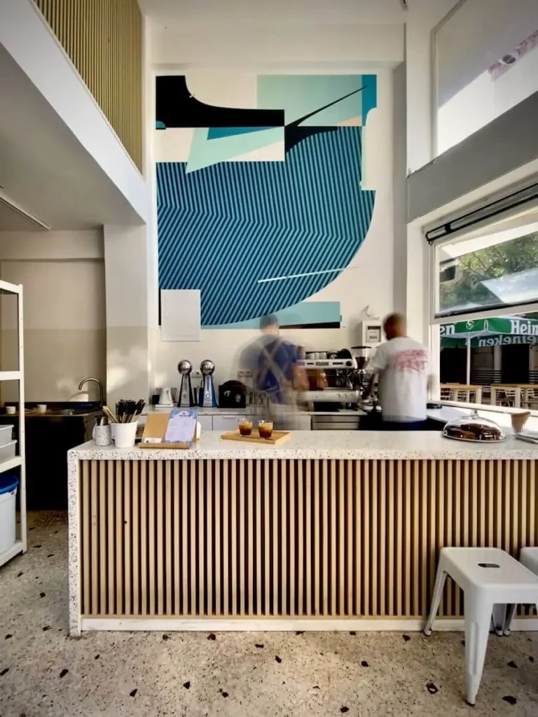 Interior day view of Myller Coffeeshop, with two baristas behind the counter preparing coffees.