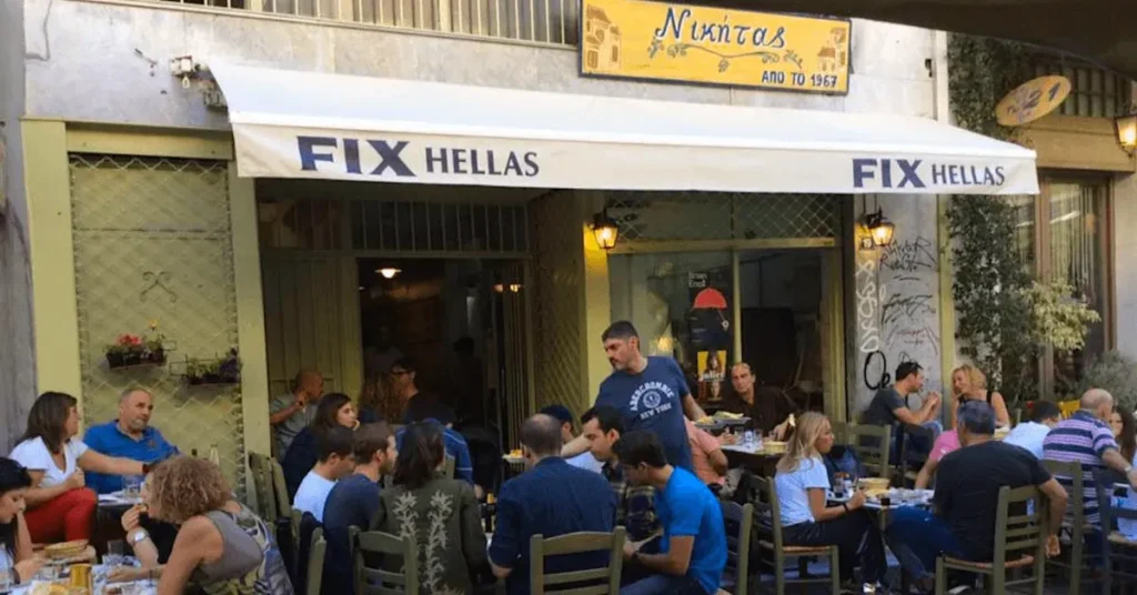 Street view of Nikitas restaurant in Psiri Athens during busy hour with tables full with patrons enjoying their food.