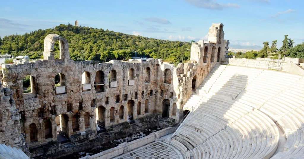 The Odeon of Herodes Atticus in Athens under bright daylight, showing its ancient stone tiers and stage.