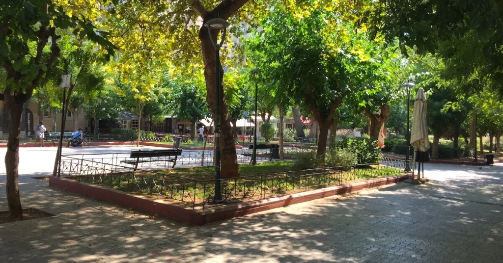 Kypseli Athens Travel Guide: Panoramic view of part of Fokionos Negri pedestrian street in Kypseli with a few benches under the shade of the trees