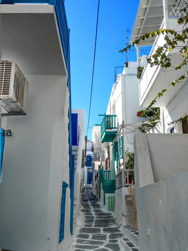 Traditional narrow alley with white houses and blue balconies in Mykonos Town.