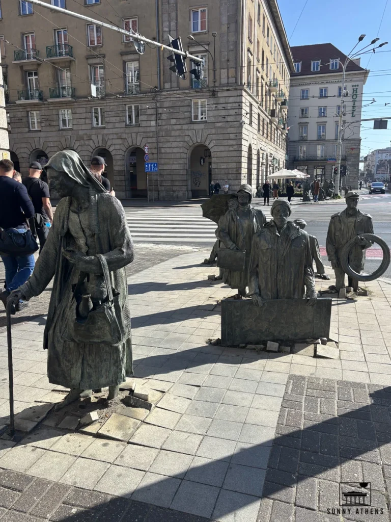 Bronze sculptures of people emerging from and sinking into the pavement in Wroclaw.