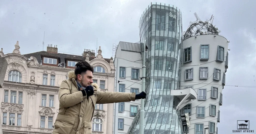 Standing in front of Prague's Dancing House striking a funny fighting pose against a snowy, overcast sky.