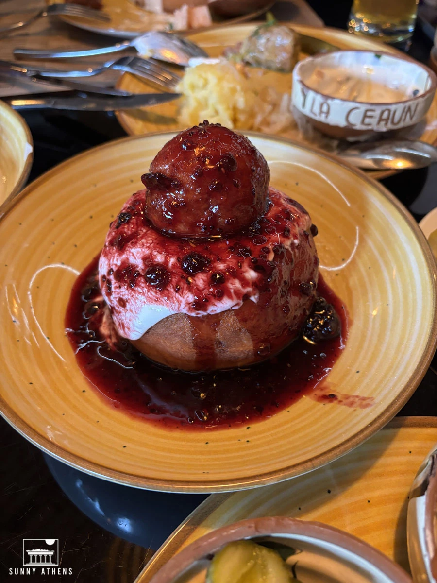 A delicious serving of papanasi, a traditional Romanian dessert topped with sour cream and dark berry jam.