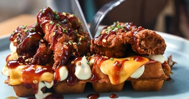 a close up of a waffle with breaded chicken on top