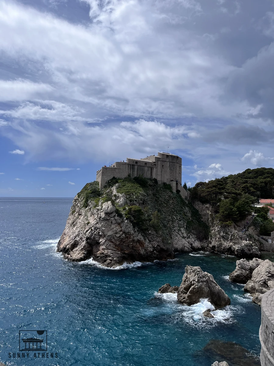 The massive stone ramparts of Fort Lovrijenac perched on a high rocky cliff above the churning blue waters of the Adriatic