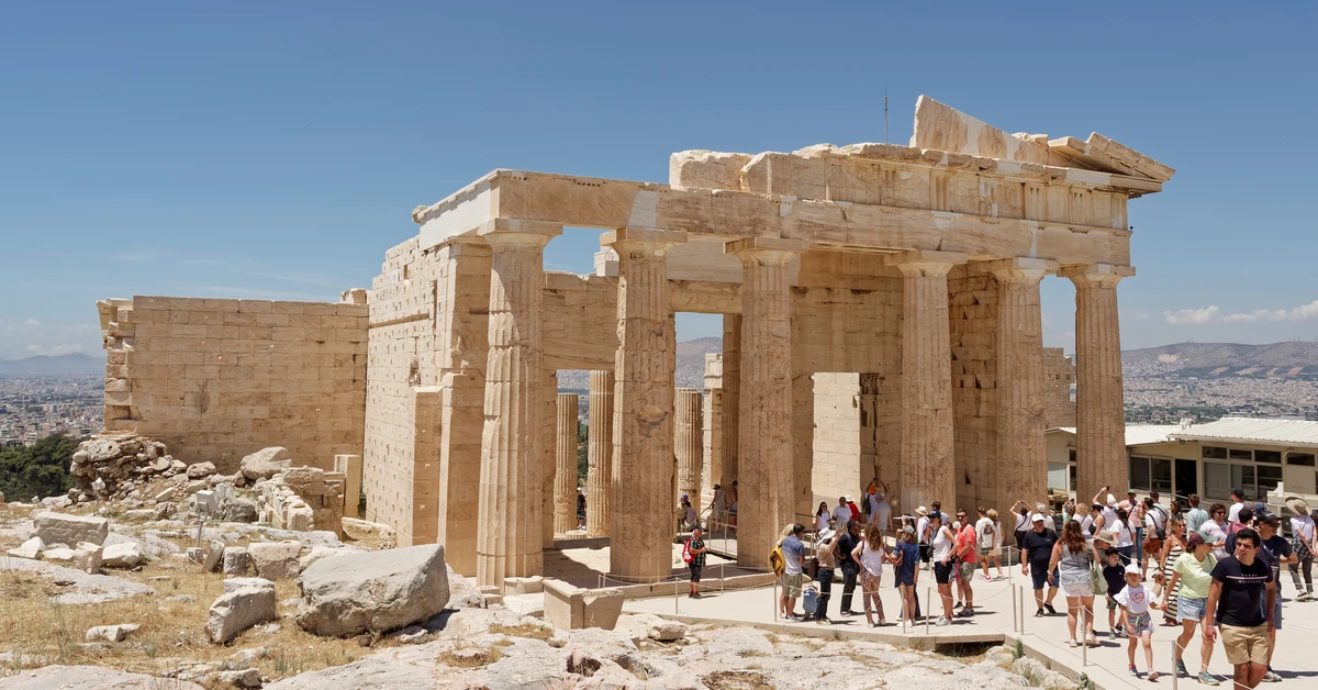 Visitors walking through the monumental Doric columns of the Propylaea gateway at the Acropolis in Athens