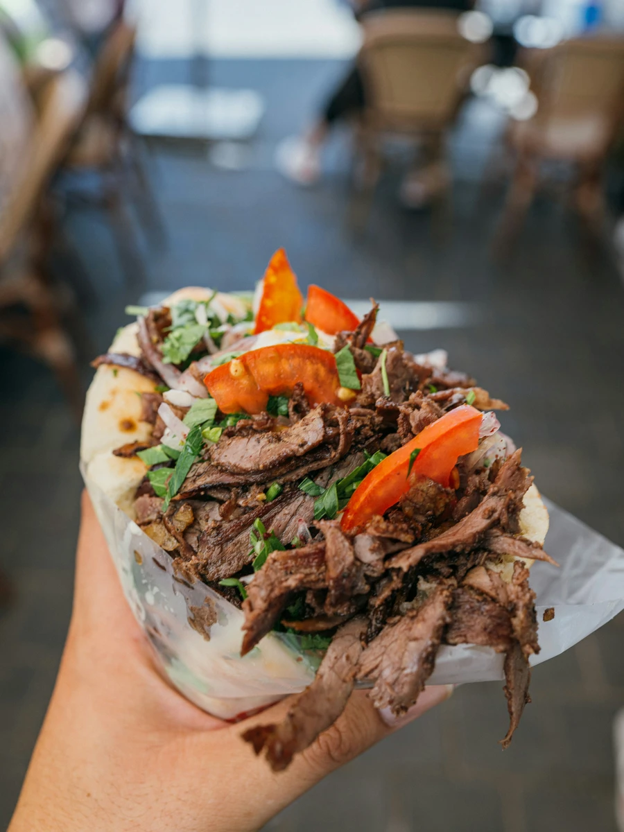 Traditional souvlaki pita wrap with thinly sliced meat, fresh tomato, and parsley in Athens