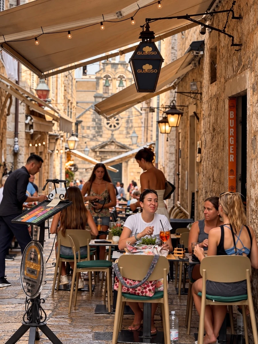 Outdoor dining tables and hanging lanterns along the stone staircase of Boskoviceva street outside Food Bar Guloso
