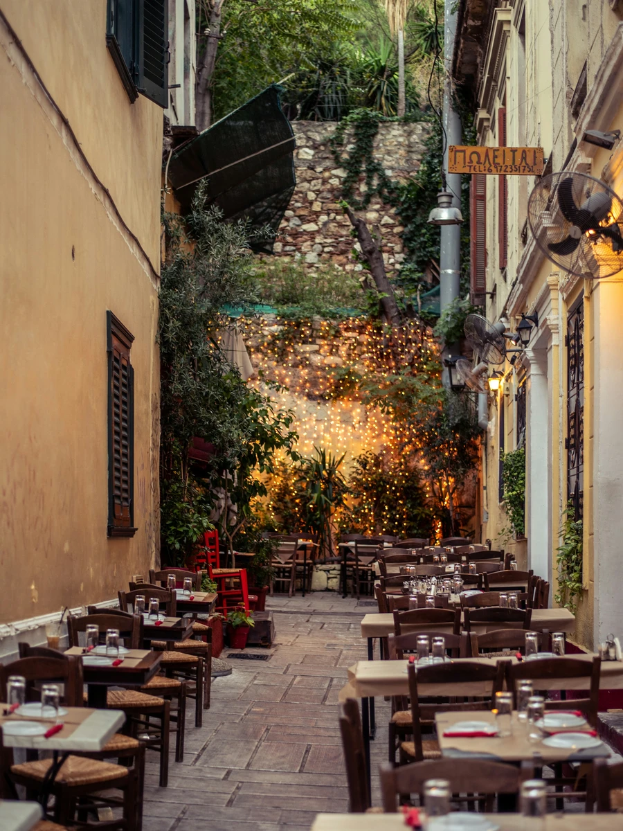 Pedestrian alleyway with traditional tavern tables and chairs in central Athens