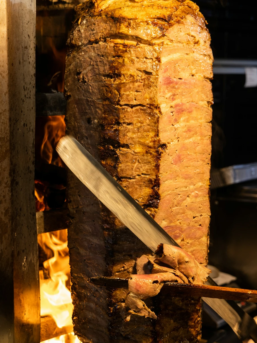 Traditional gyro meat roasting on a vertical spit over an open flame