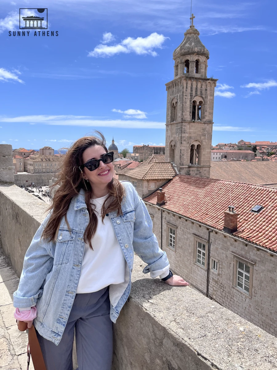 Chrysavgi on the City Walls with the tall stone bell tower of the Dominican Monastery and the harbor in the background