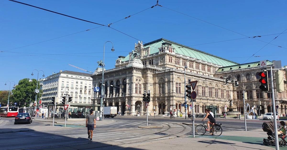 The exterior neo-Renaissance facade of the Vienna State Opera viewed from the street under a blue sky
