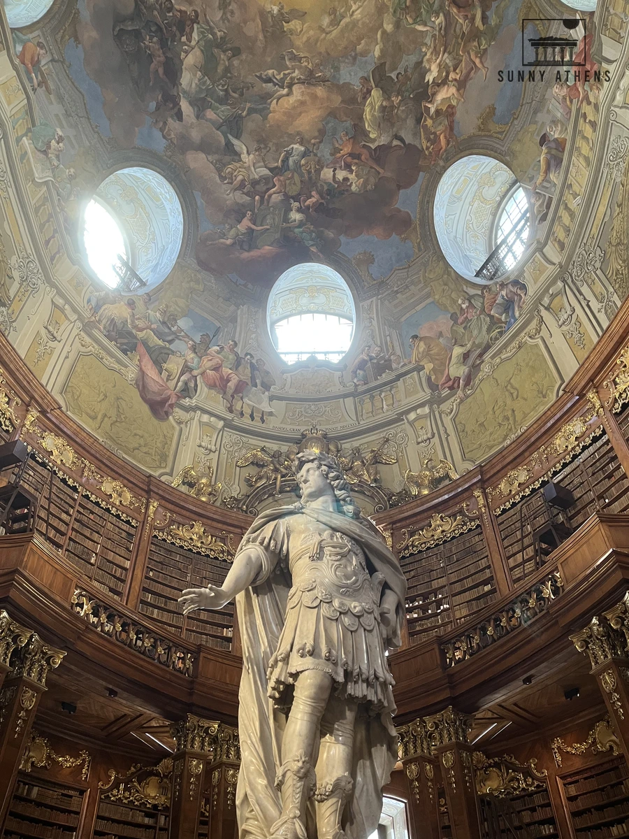 The marble statue of Emperor Charles VI beneath the painted dome of the Austrian National Library State Hall