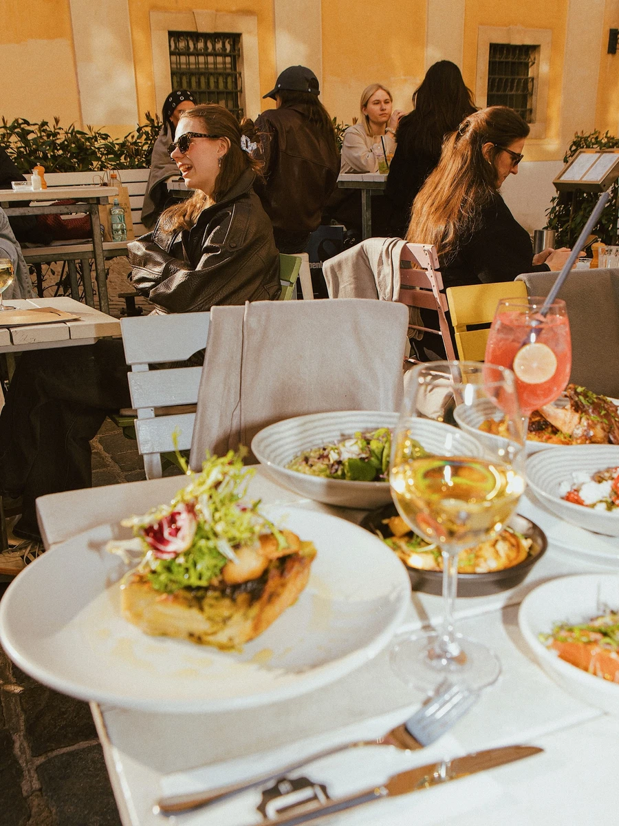 Outdoor dining table with savory dishes, salad, and wine glasses at Ulrich restaurant in Vienna