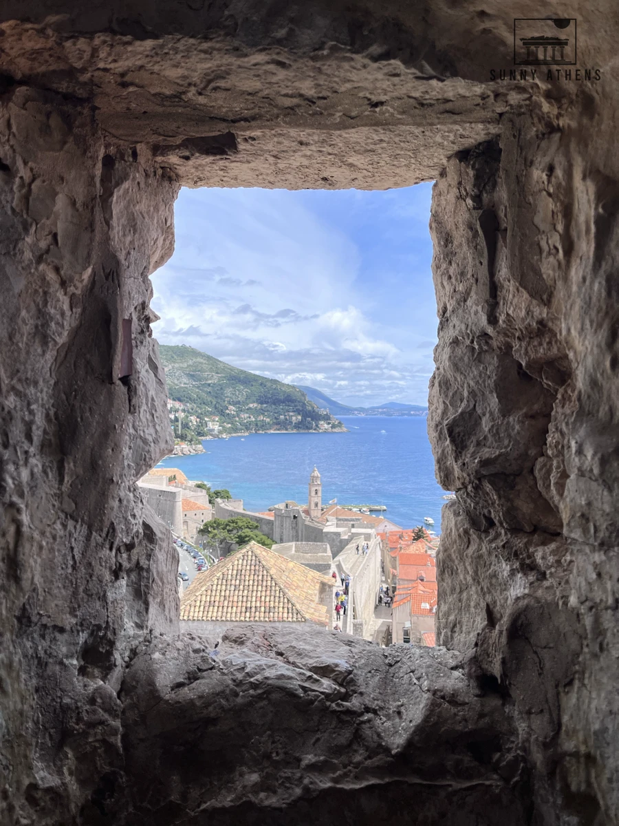 Stone fortress embrasure window along the Dubrovnik City Walls framing a view of Lokrum Island and the Adriatic Sea